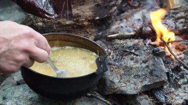 Doğadaki maceralar. Basit bir yemek. Hayatta kalmak. Adam ateşte pişirilen çorbaya dondurulmuş patatesler ekler. Sibirya.