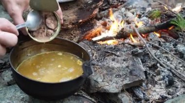 Doğadaki maceralar. Basit bir yemek. Hayatta kalmak. Adam ateşte pişirilen çorbaya konserve balık ekler. Sibirya.