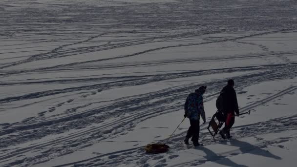 人们在冰雪覆盖的冰封的西伯利亚奥布河上漫步 背光照明 — 图库视频影像
