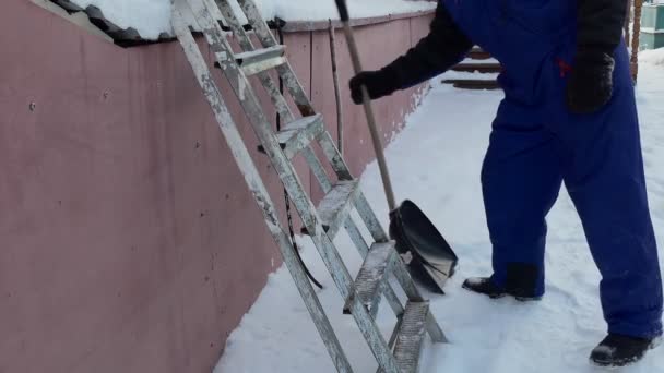 雪のクリアランス 男は雪のシャベルで家のガレージから雪をダンプするために階段を登る シベリア — ストック動画