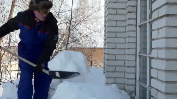 雪のクリアランス 青い会社の男はガレージから雪のシャベルをリセットします シベリア — ストック動画