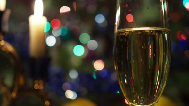 圣诞节 在香槟酒杯中 在蜡烛和闪烁的彩灯的衬托下 泡沫四起 背景录像 靠近点 — 图库视频影像