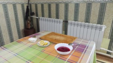 Basit yemek, turta yapmak. Bir kadın mutfak masasının üzerine acı krema, reçel ve limonlu tabaklar koyuyor. Genel plan. Sibirya.