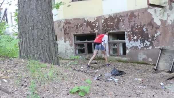 仮の場所だ 若い女性サイクリストは森の中の古い破壊された建物を検査します 壊れた窓の中だ シベリア — ストック動画