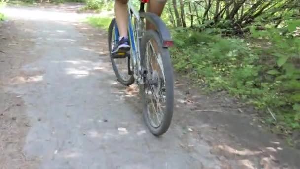 Žena na kole na opuštěné asfaltové dráze v lese. Doprovázet pohyblivou kameru. Zavřít. Sibiř.