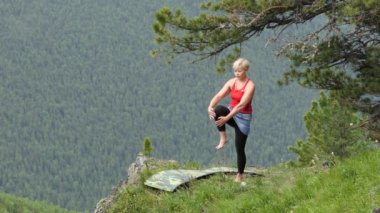 Ashram yogası. Bireysel aktivite. Doğadaki maceralar. Genç bir kadın dağlarda Ashram yoga teknikleri uyguluyor, dengesini dengesiz bir yüzeyde tutmaya çalışıyor. Sibirya.