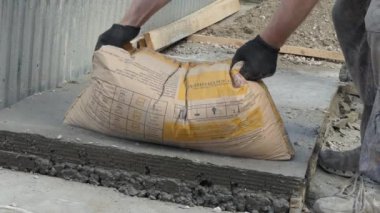 Beton evde işe yarar. Bir adam çimento çantasını boşaltıyor.