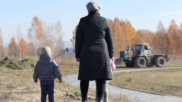 아이들 할머니와 자녀들은 근처를 지나가는 트랙터를 바라본다 — 비디오