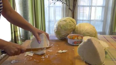 Vejetaryenlik. Basit bir yemek. Bir kadın tuzlamak için lahana kafasını bıçakla kesiyor..