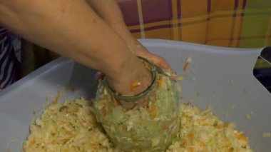 Vejetaryenlik. Basit bir yemek. Ev konservesi. Kadın cam bir kavanoza koyar ve tuzlamak için dilimlenmiş lahana koyar. Kapatın. Yakınlaştırılıyor.