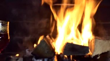 Noel, yeni yıl. Bir şenlik düzeneği. Şömine ateşinin arka planında içki bardakları zum yapıyor. Kapat..