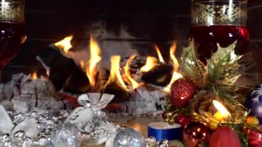 Noel, yeni yıl. Bir şenlik düzeneği. Şömine ateşinin arka planında içki bardakları zum yapıyor. Kapat..