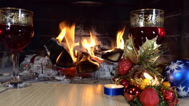 圣诞节 一个节日的装置 玻璃杯 在壁炉的火焰的背景上 有一杯饮料和圣诞装饰 靠近点 — 图库视频影像