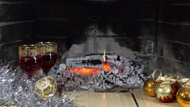 圣诞节 一个节日的装置 玻璃杯 在壁炉的火焰的背景上 有一杯饮料和圣诞装饰 靠近点 — 图库视频影像