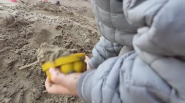 Yavrum. Kumda oyuncaklarla oynayan bir çocuğun elleri. Yakın çekim..