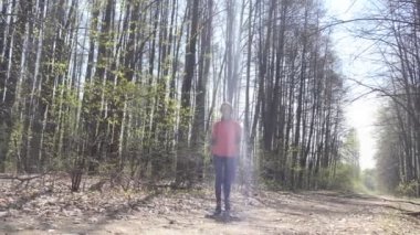 Kendini soyutlama. Tıbbi maskeli ve bisiklet eldivenli bir kadın kendini izole ederken parktaki ağaçların arasında sırt çantasıyla tek başına yürüyor..