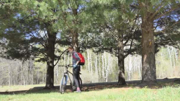 自己分離 医療用マスクの自己分離の女性はシベリア杉の間の公園で徒歩で彼女の自転車をリード — ストック動画