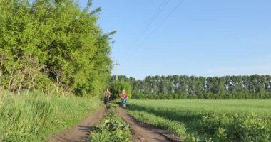 Bisikletçiler, bisikletler. Bir adam ve bir kadın kırsal kesimde bir tarla yolunda bisiklet sürüyorlar..