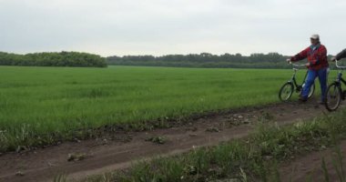 Bisikletçiler, bisikletler. Mutlu bir adam ve kadın bisikletlerini kırsal bir yolda sürüyor ve konuşuyor..