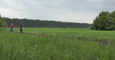 Bisikletçiler, bisikletler. Bir adam ve bir kadın kırsal kesimde bir tarla yolunda bisiklet sürüyorlar..