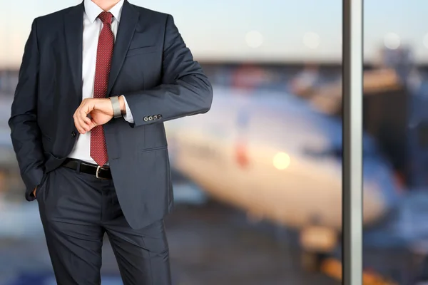 Empresário segurando pasta de couro verificando o tempo em seu relógio no aeroporto — Fotografia de Stock