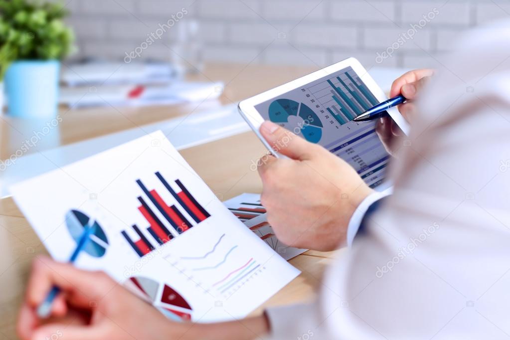 Business colleagues working and analyzing financial figures on a graphs