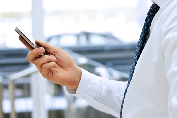 Cropped view of Businessman holding the mobile  phone standing in front the window — Stock Photo, Image