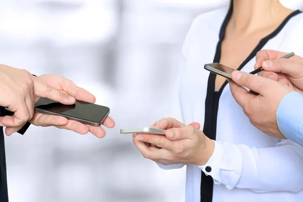 Primer plano de un hombre y una mujer de negocios que utilizan teléfonos inteligentes móviles — Foto de Stock