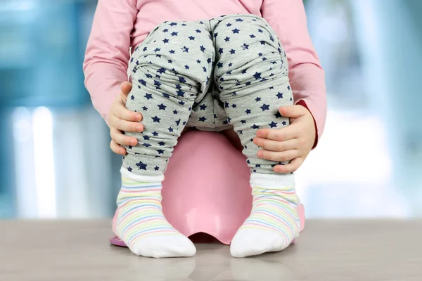 Las piernas de los niños que cuelgan de un orinal sobre un fondo azul —  Fotos de Stock