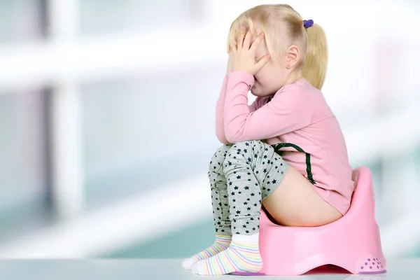 Kinderbeine hängen aus einem Kammertopf auf blauem Hintergrund herunter — Stockfoto