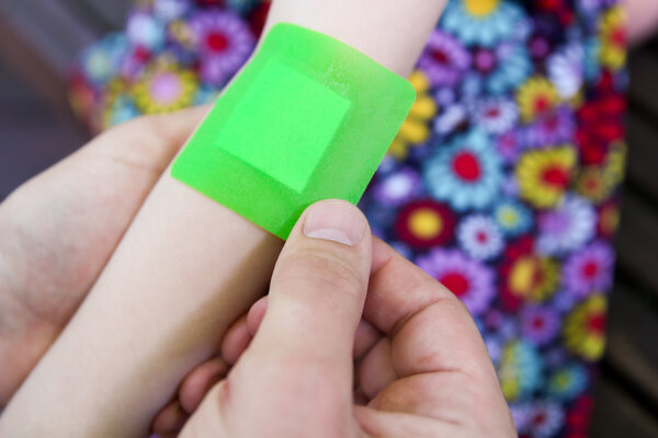 Man putting to girl plaster on the sore arm