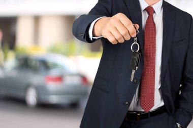 Bir araba anahtarı sunan başarılı bir iş adamı. Sürücünün el gösteren anahtar Close-Up