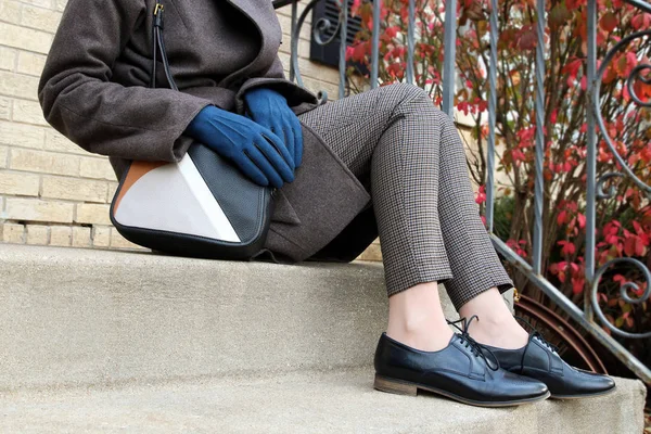 Elegáns nő ül a lépcsőn, a gyapjú kabátot, fekete klasszikus modern cipő és táska — Stock Fotó