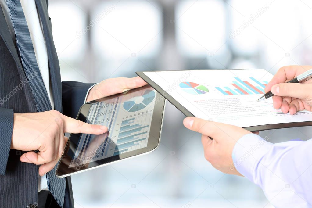 Business colleagues working and analyzing financial figures on a digital tablet