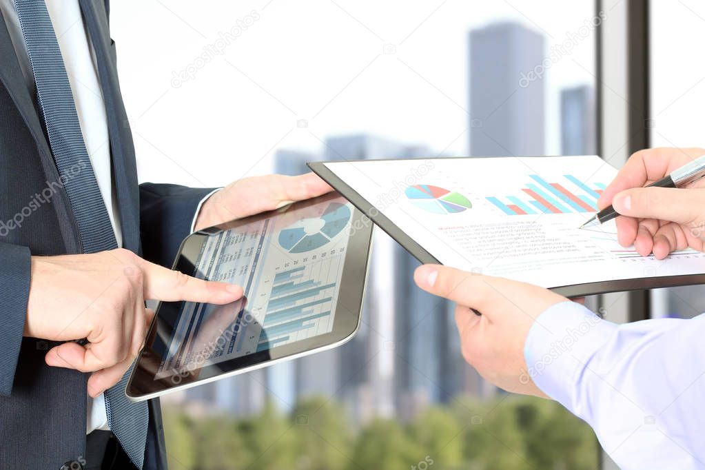 Business colleagues working and analyzing financial figures on a digital tablet