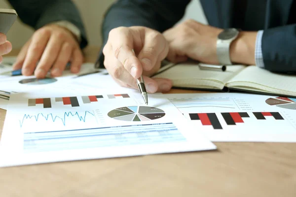 Geschäftskollegen arbeiten zusammen und analysieren Finanzzahlen auf einer Grafik — Stockfoto