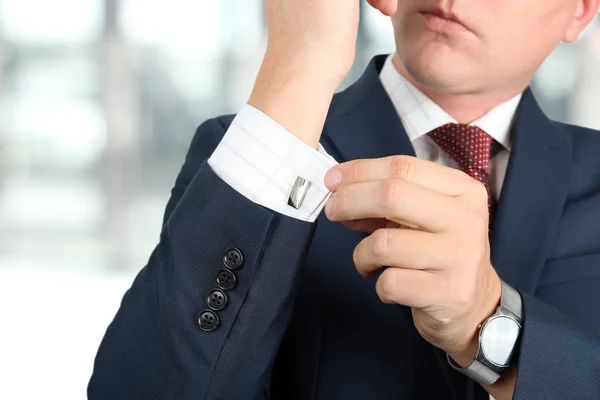 Business and office concept -  elegant young fashion  buisness man in  a blue/navy suit touching at his cufflinks — Stock Photo, Image