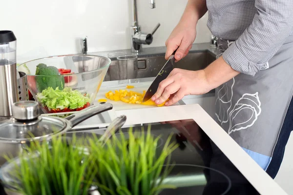 Comida, família, cozinhar e conceito de pessoas - Homem cortando páprica na tábua de corte com faca na cozinha — Fotografia de Stock