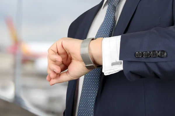 Biznesmen sprawdzania czasu na swój zegarek na lotnisku — Zdjęcie stockowe