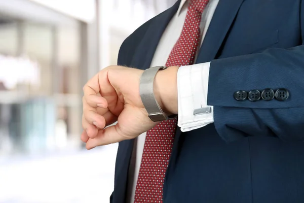 Hombre de negocios que sostiene el maletín de cuero comprobando el tiempo en su reloj en la oficina —  Fotos de Stock