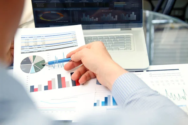 Business man working and analyzing financial figures on a graphs using laptop — Stock Photo, Image