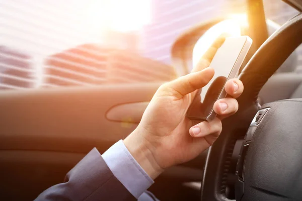 El hombre de negocios que utiliza el teléfono inteligente móvil mientras conduce el coche —  Fotos de Stock