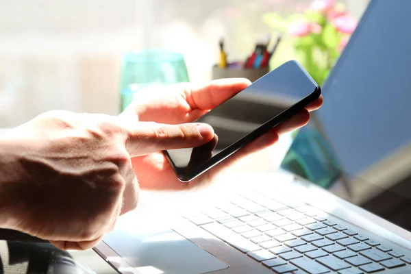 Mann benutzt ein modernes Mobiltelefon mit Laptop — Stockfoto