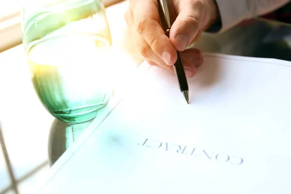 Hombre de negocios está firmando un contrato sentado en la oficina —  Fotos de Stock