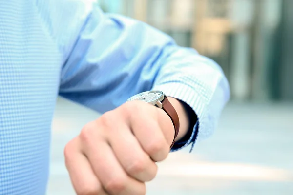 Empresário verificando o tempo em seu relógio perto com escritório — Fotografia de Stock