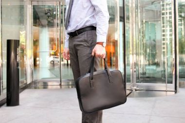 Ayakta ve deri evrak çantası elinde tutan işadamı