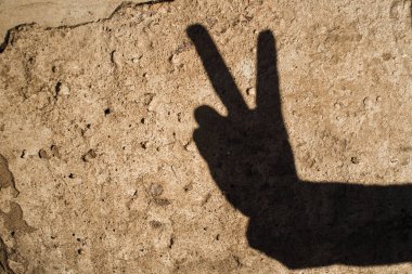 Doku duvarında bir gölge şeklinde bir barış işareti. Dünya barışının jesti
