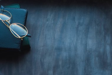 Koyu renk bir arka planda dizüstü bilgisayar ve gözlük kompozisyonu. Kopyalama alanı ile Üst Görünüm