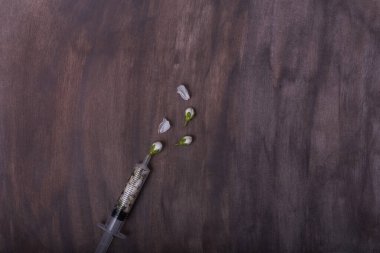  İçinde kiraz çiçekleri olan tıbbi bir şırınga ve koyu renkli bir arka planda koruyucu bir maske.