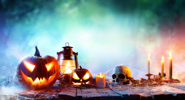Halloween - Lanterns And Pumpkins On Wooden Table In A Haunted Forest
